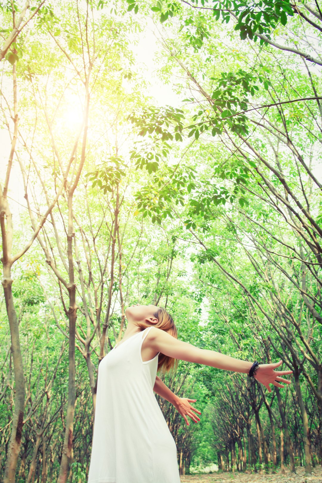 Mujer con los brazos abiertos en un bosque