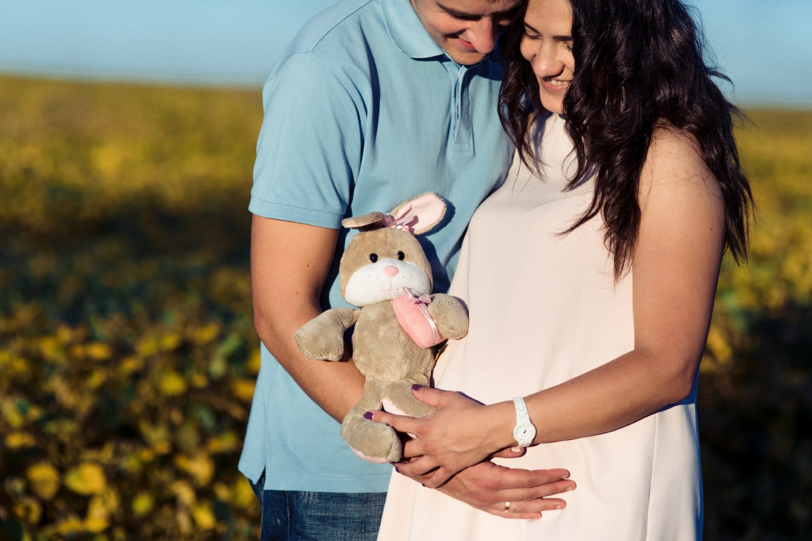 Pareja abrazada, ella embarazada, en el campo