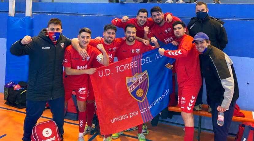 Jugadores de la U.D. Torre del Mar posan con la bandera del club junto al banquillo