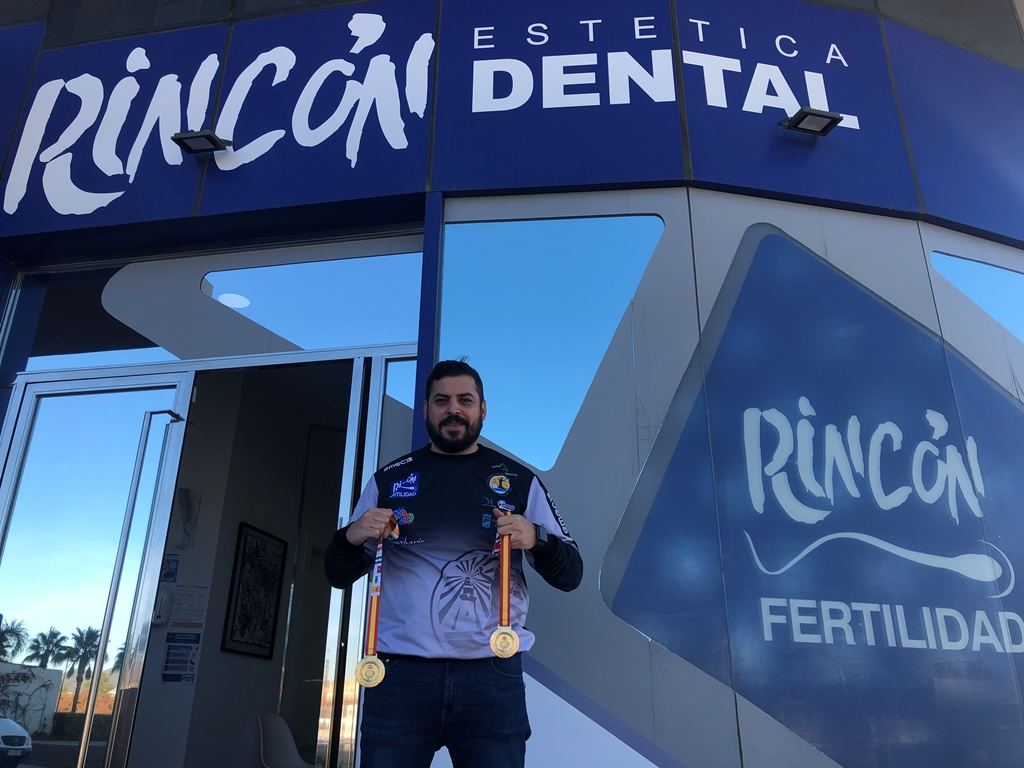 Un deportista posa con sus medallas en la entrada de la clínica Rincón Dental y Rincón Fertilidad