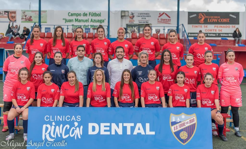 Plantilla del equipo femenino de la U.D. Torre del Mar en el campo Juan Manuel Azuaga, con la valla de Clínicas Rincón Dental