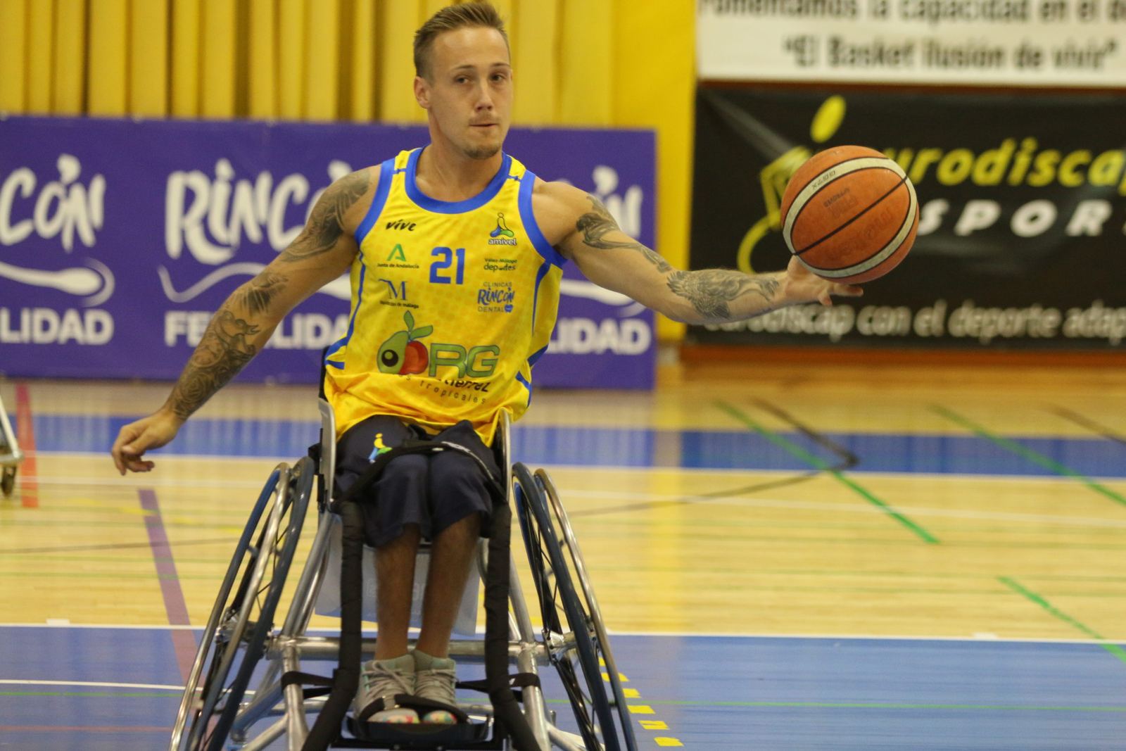 Jugador de baloncesto en silla de ruedas bota el balón ante la valla de Rincón Fertilidad