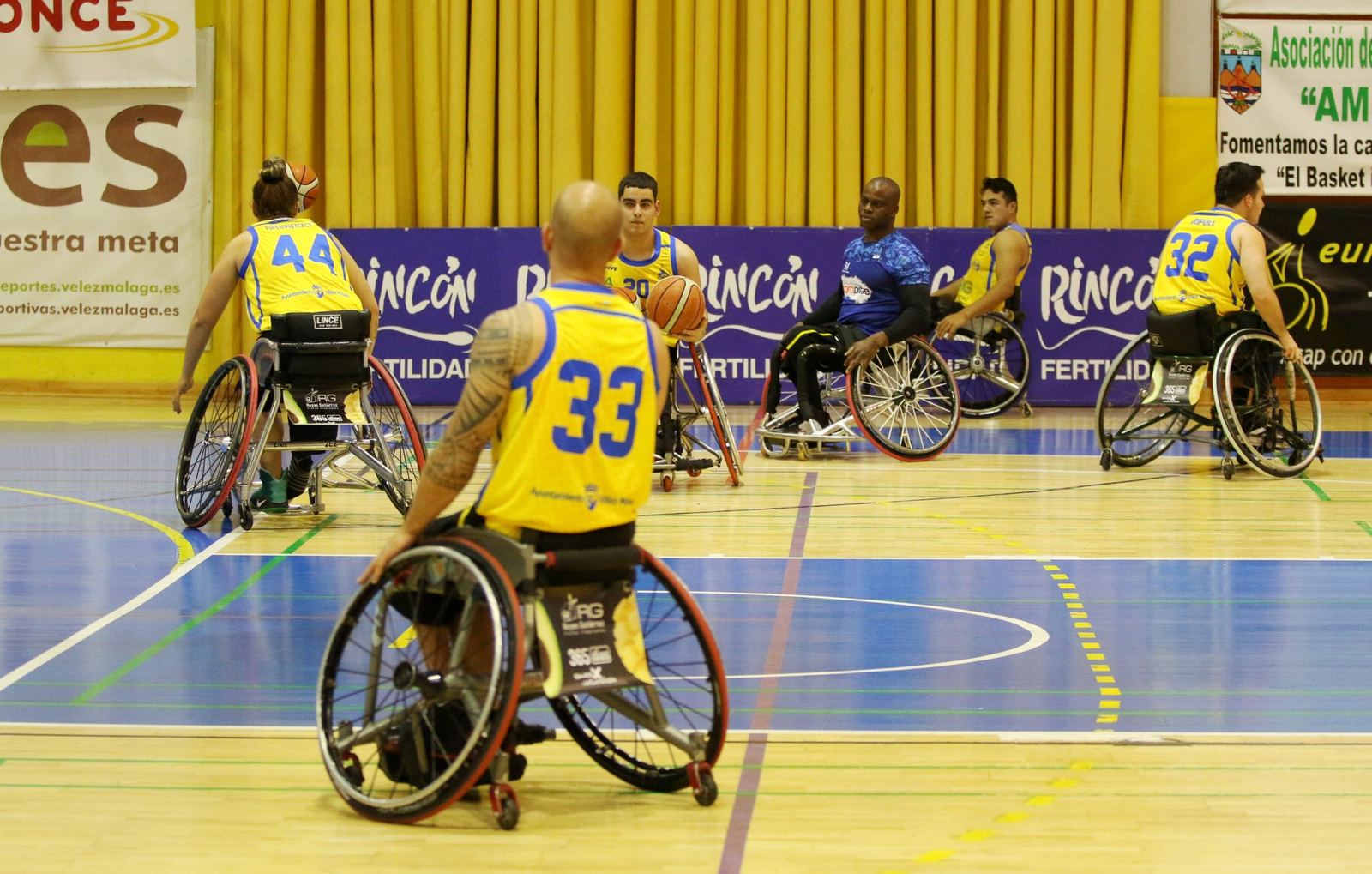 Partido de baloncesto en silla de ruedas ante la publicidad de Rincón Fertilidad