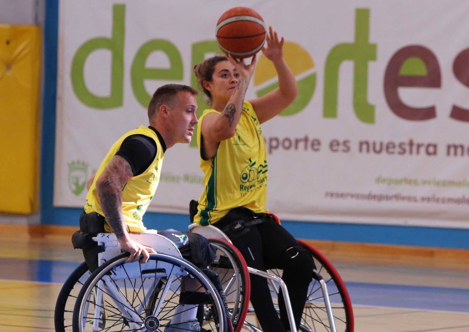 Dos jugadores de baloncesto en silla de ruedas disputan el balón bajo la canasta
