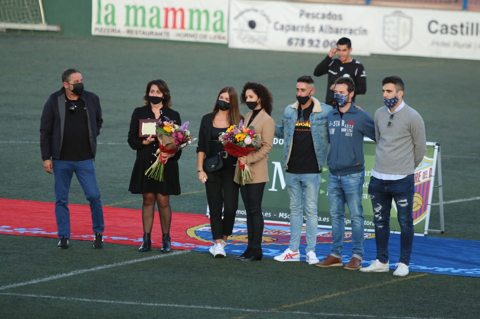 Las personas homenajeadas posan sobre el césped con sus ramos de flores
