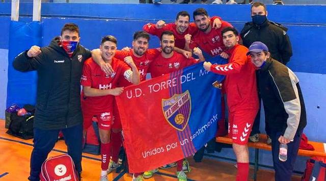 Jugadores de la U.D. Torre del Mar posan con la bandera del club junto al banquillo