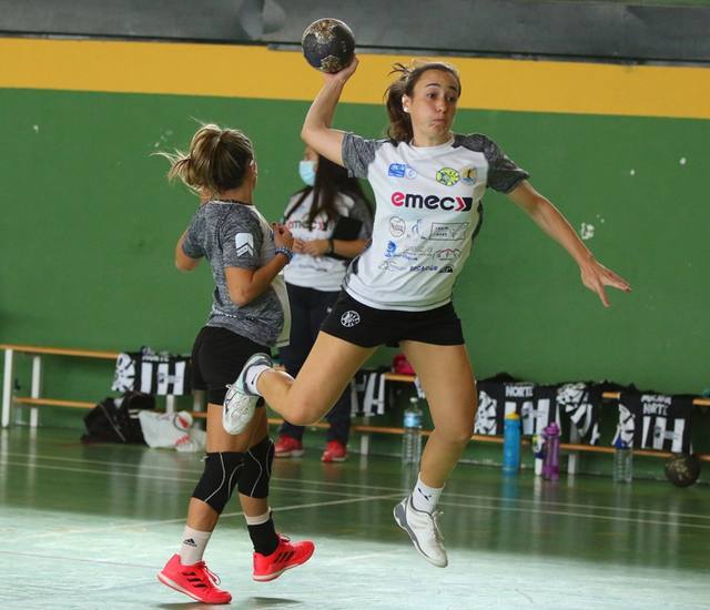 Jugadora de balonmano se eleva para lanzar ante la defensa