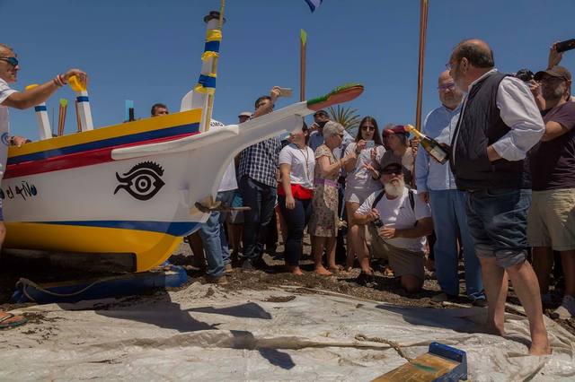 Botadura de una jábega en la playa, rodeada de público