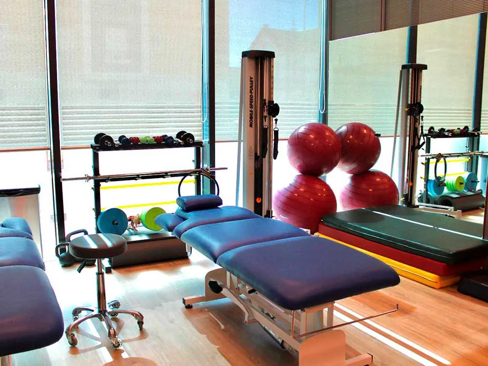Sala de fisioterapia con camillas, pesas y material de ejercicio