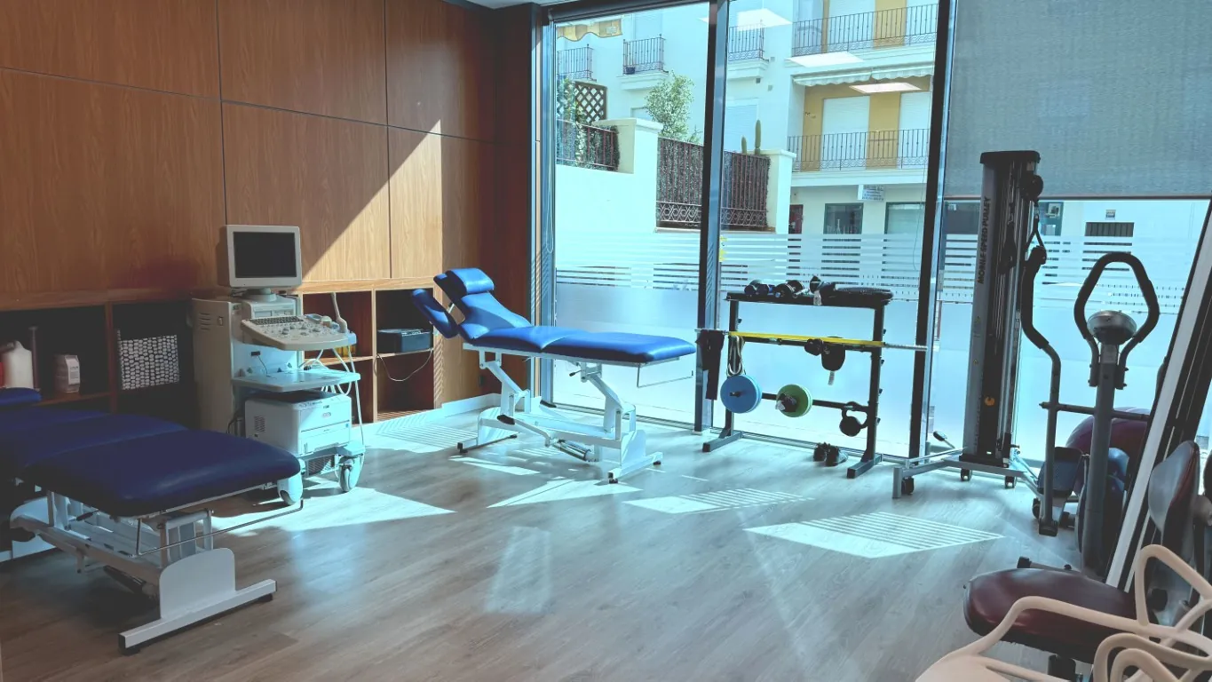 Sala de rehabilitación, con camilla y aparatos de ejercicio