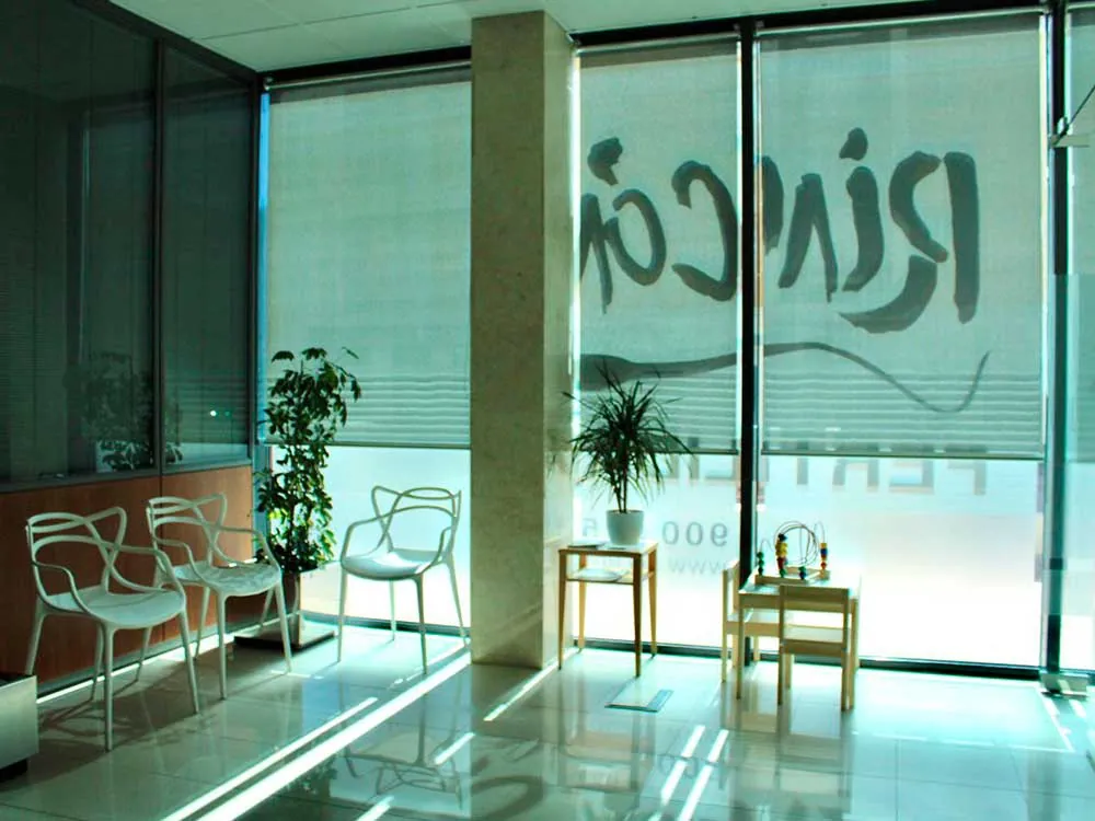Sala de espera acristalada, con luz natural y plantas